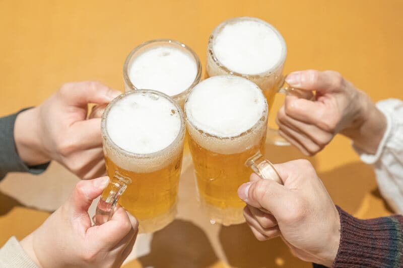 忘年会でビールジョッキを掲げて乾杯する人々