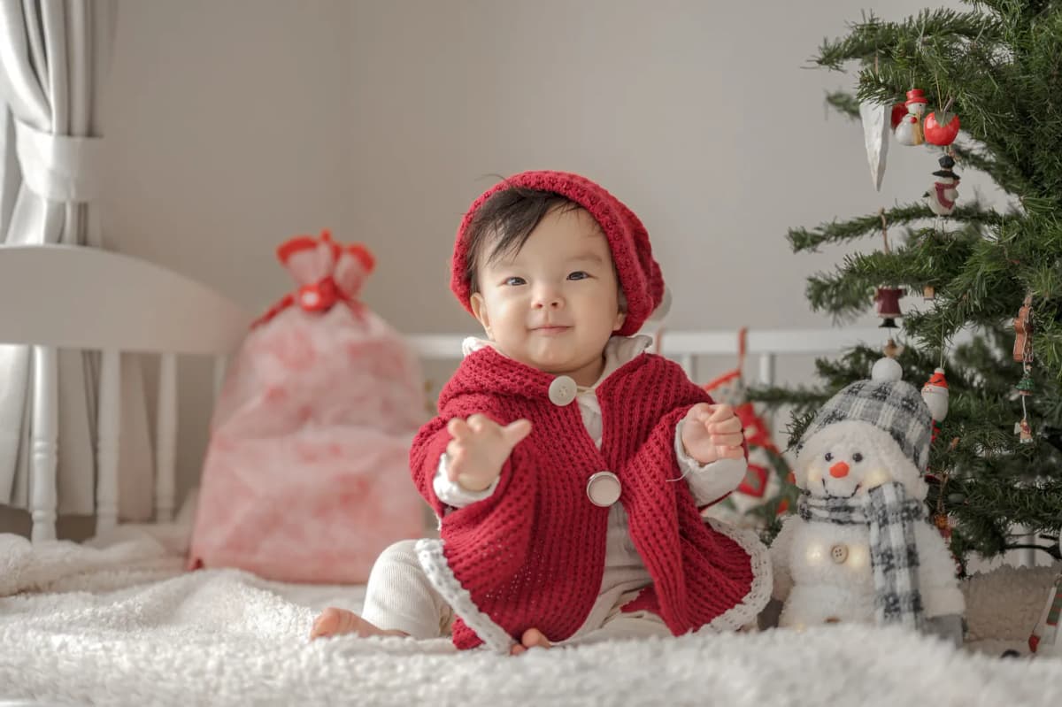 クリスマスツリーのそばに座る赤ちゃん