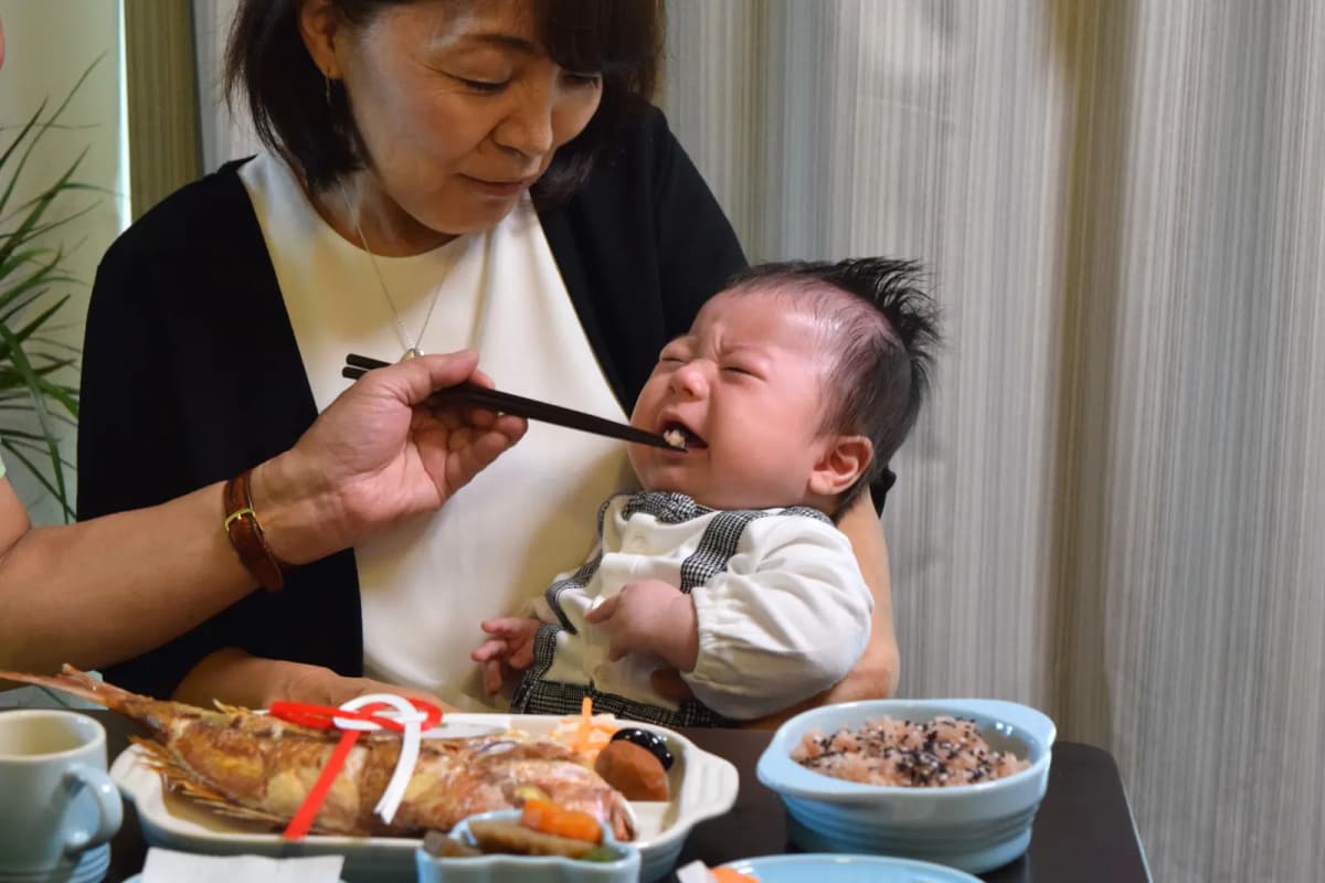 祖母に祝い膳を食べさせてもらう赤ちゃん