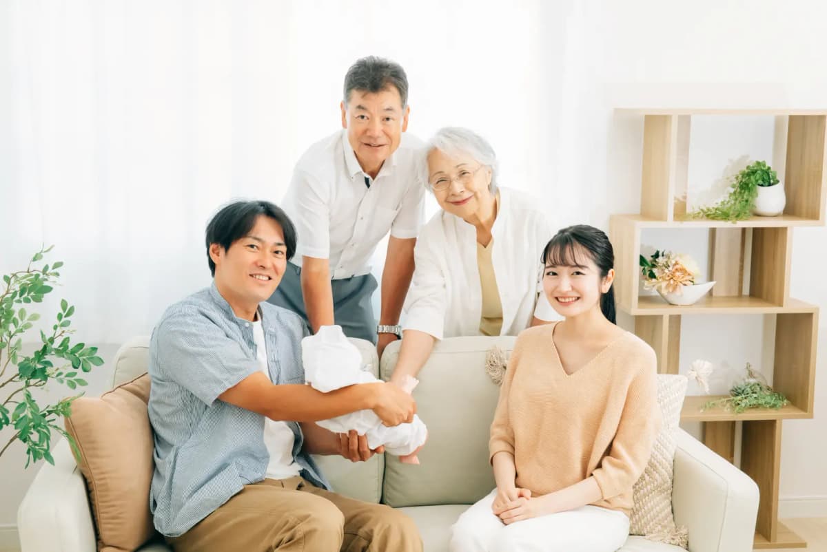 祖父母と若い夫婦が赤ちゃんを囲む様子