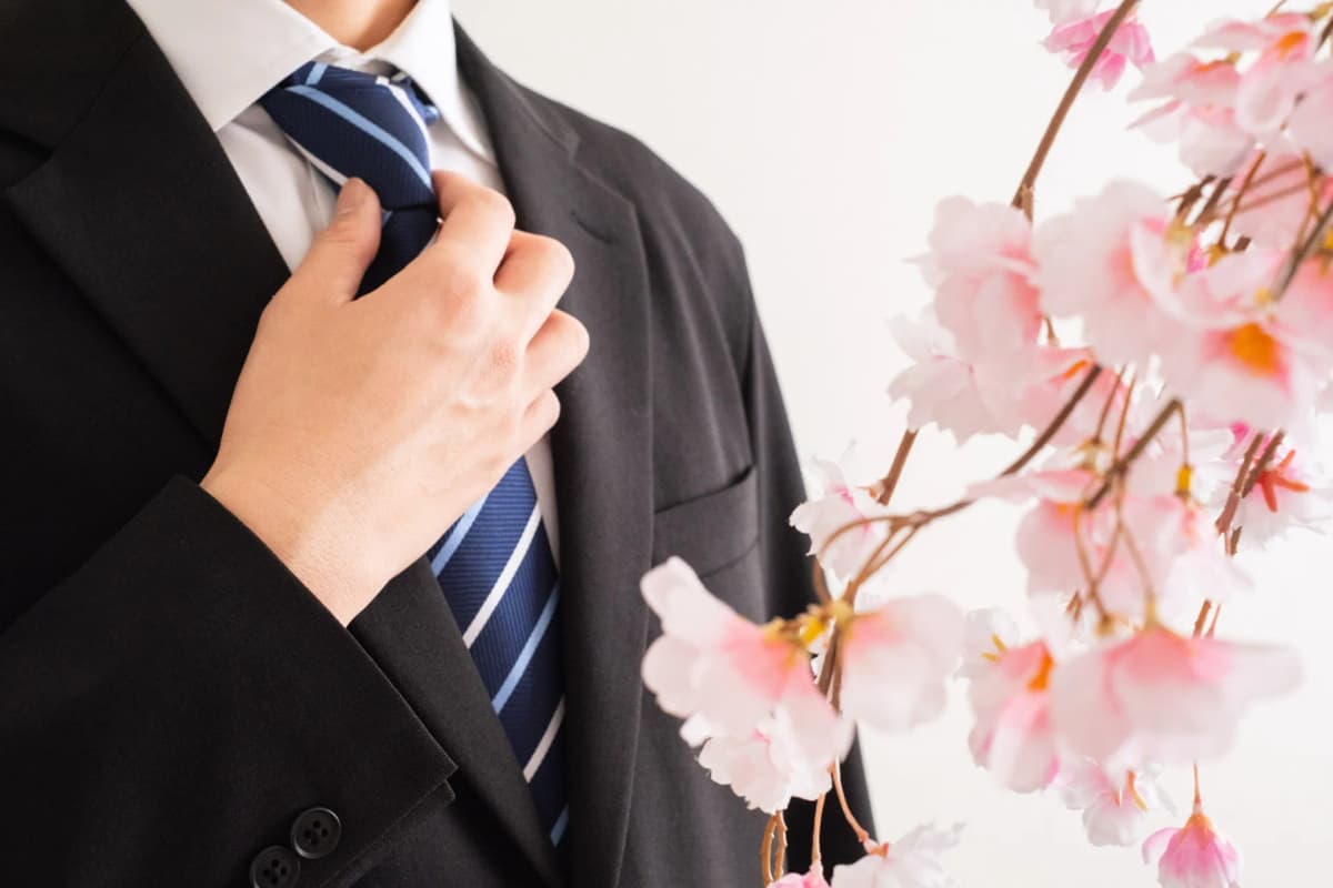 スーツにネクタイを締める男性と桜