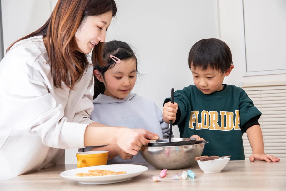 キッチンでお菓子作りをする母親と子どもたち