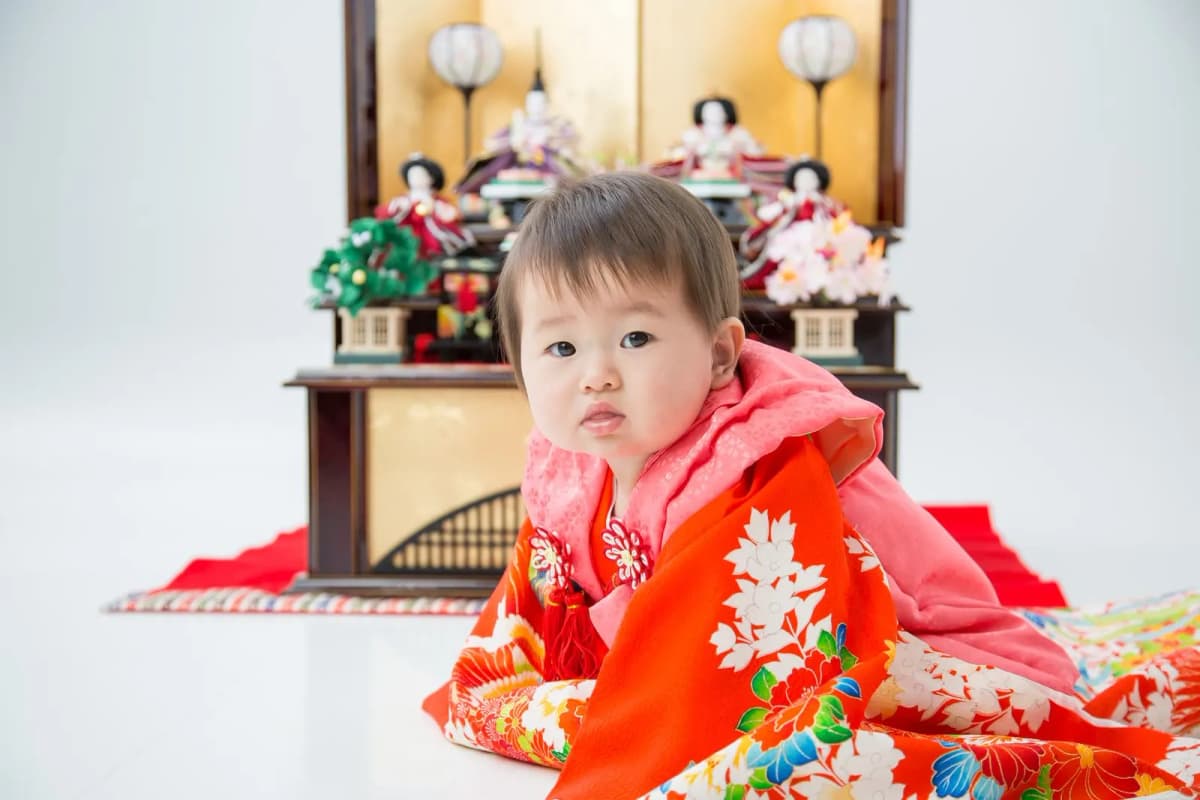 雛人形の前で赤い着物を着た赤ちゃん