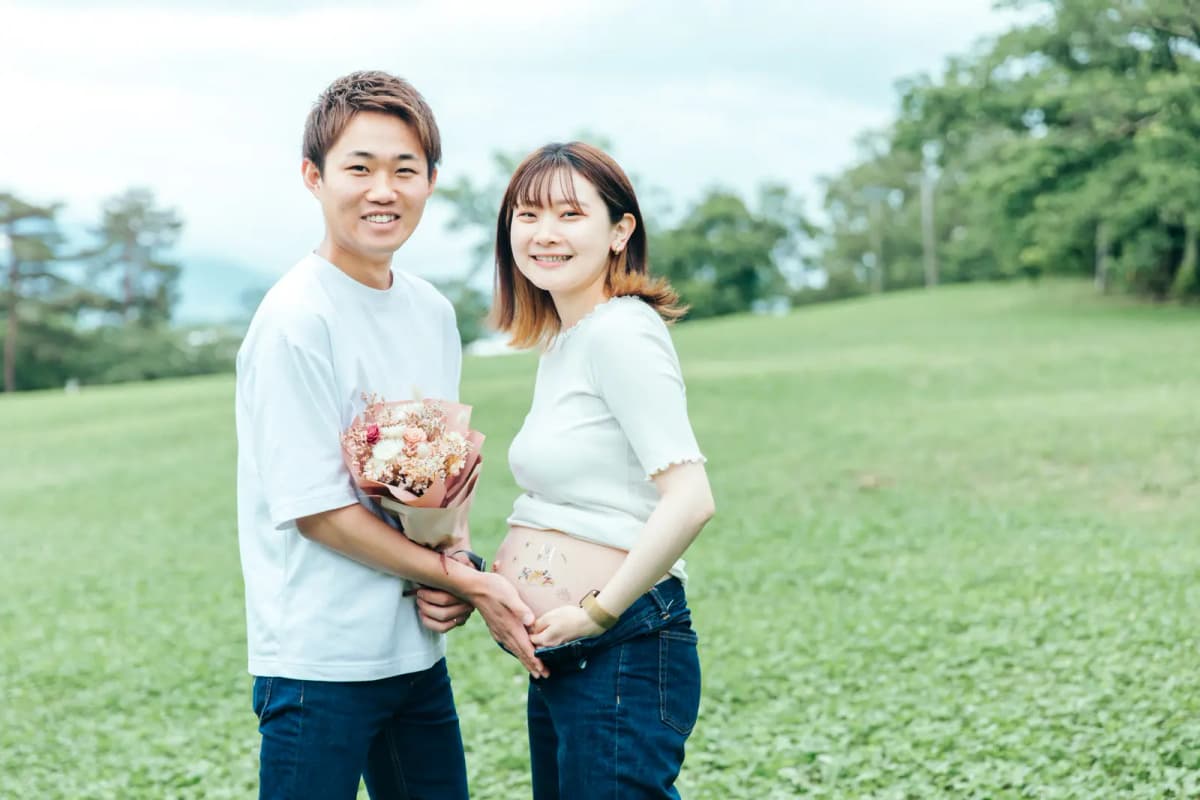 芝生の上で寄り添う妊婦と夫