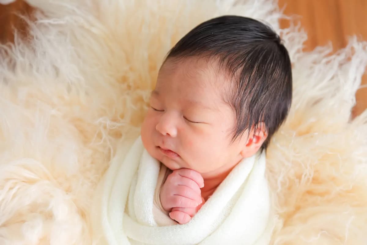 ふわふわの敷物の上で眠る新生児