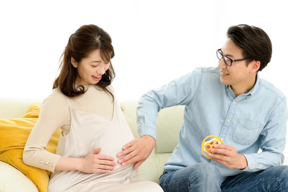 お腹に手を添えて笑い合う妊婦さんと夫