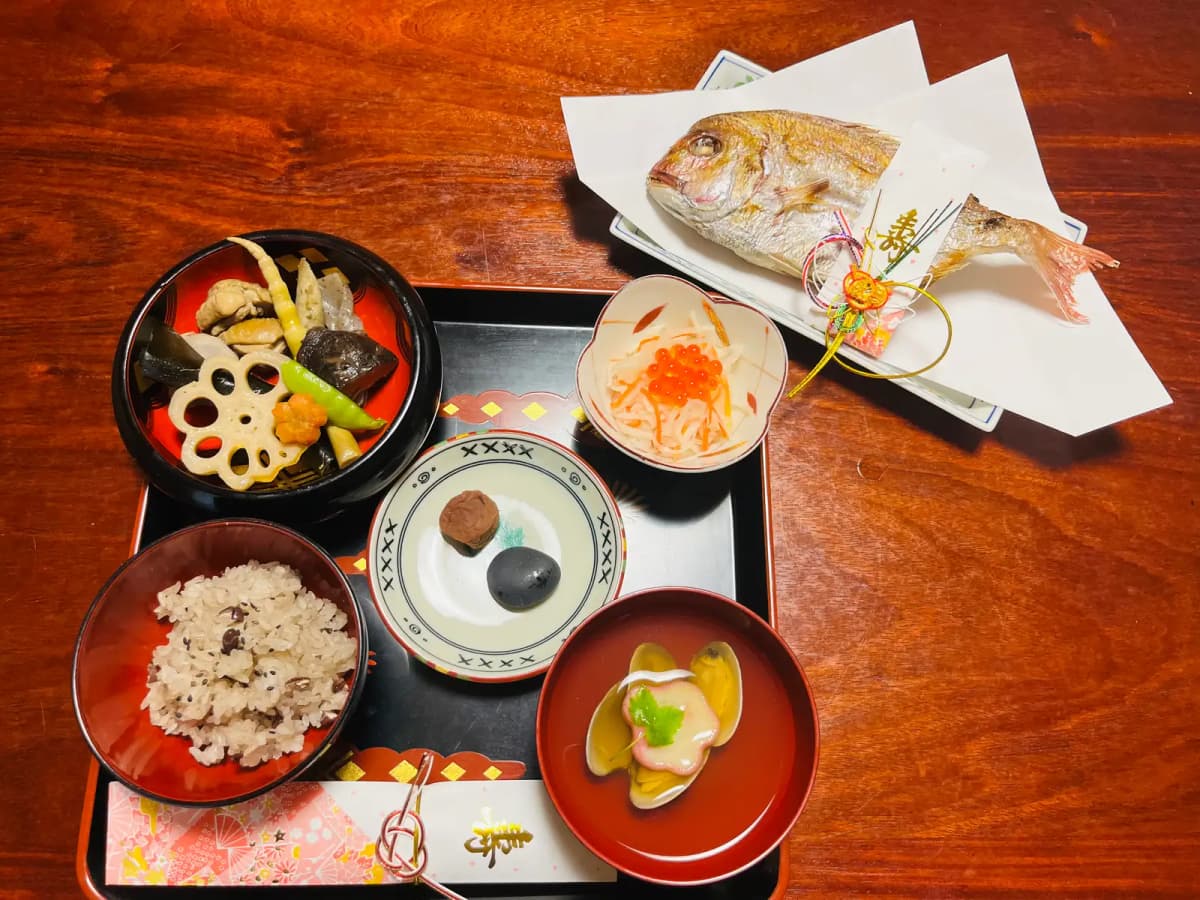 鯛と赤飯、煮物、お吸い物を並べたお食い初めの祝い膳