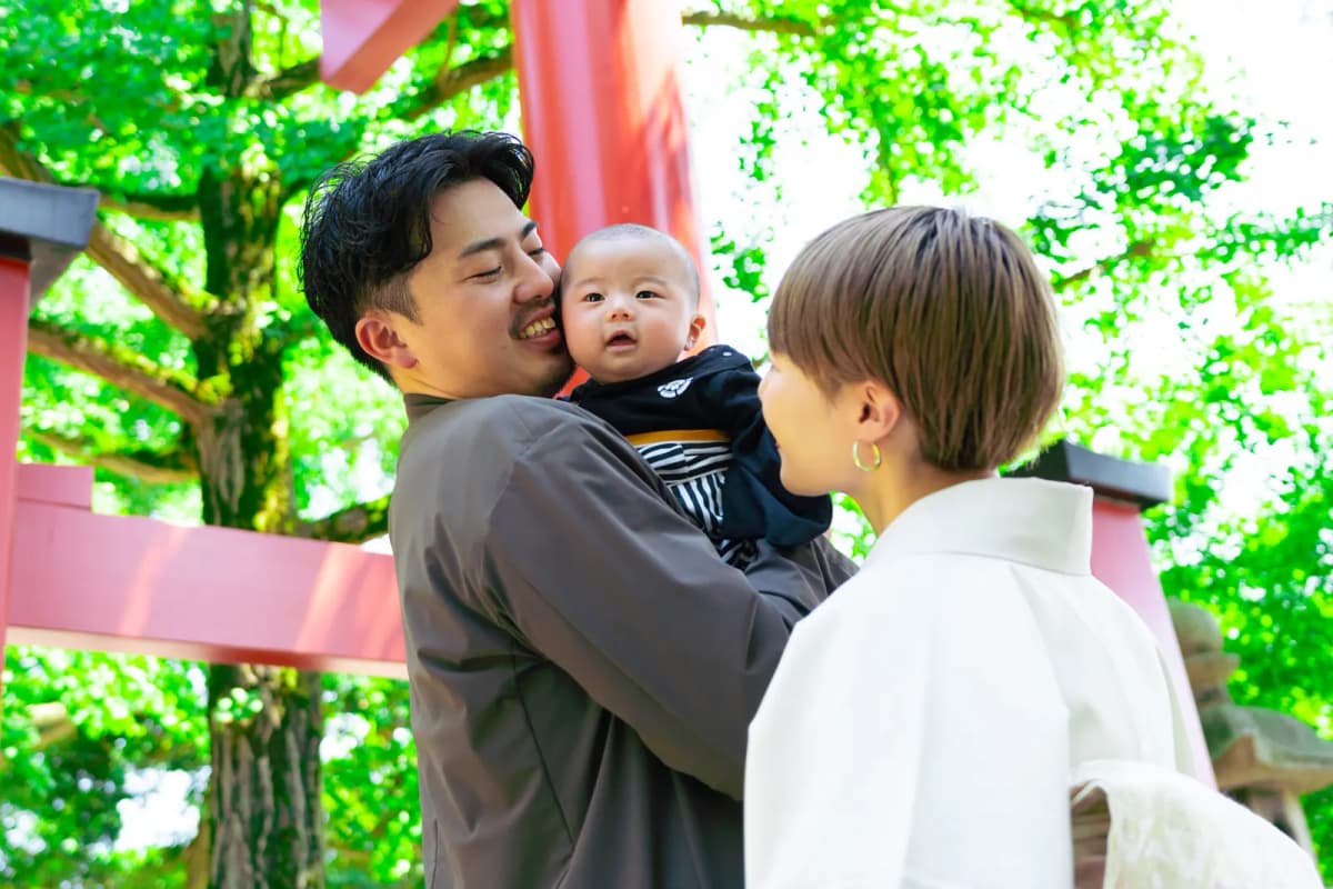 新緑の神社で赤ちゃんを抱っこするパパと母親