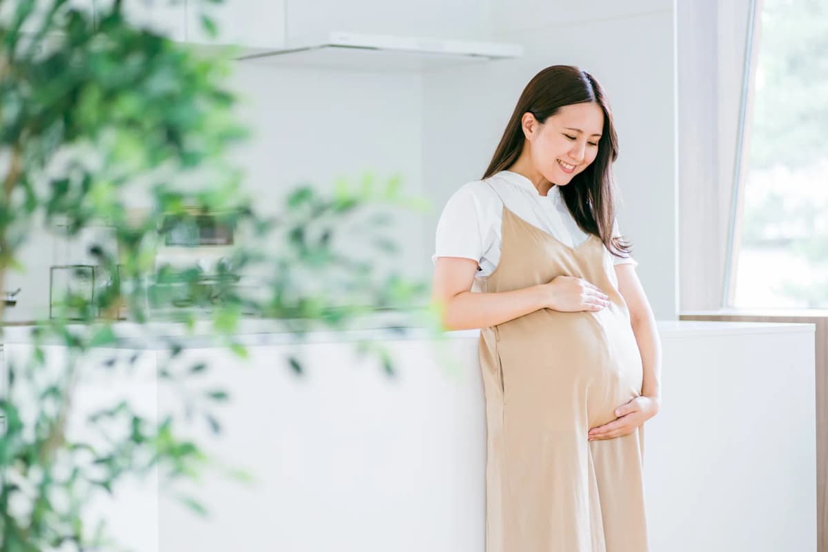お腹に手を当てて微笑む妊婦
