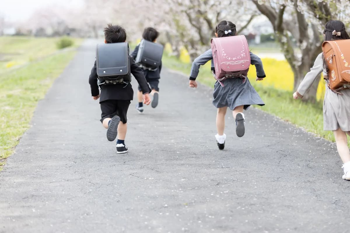 いろいろな色のランドセルを背負って走る子どもたち