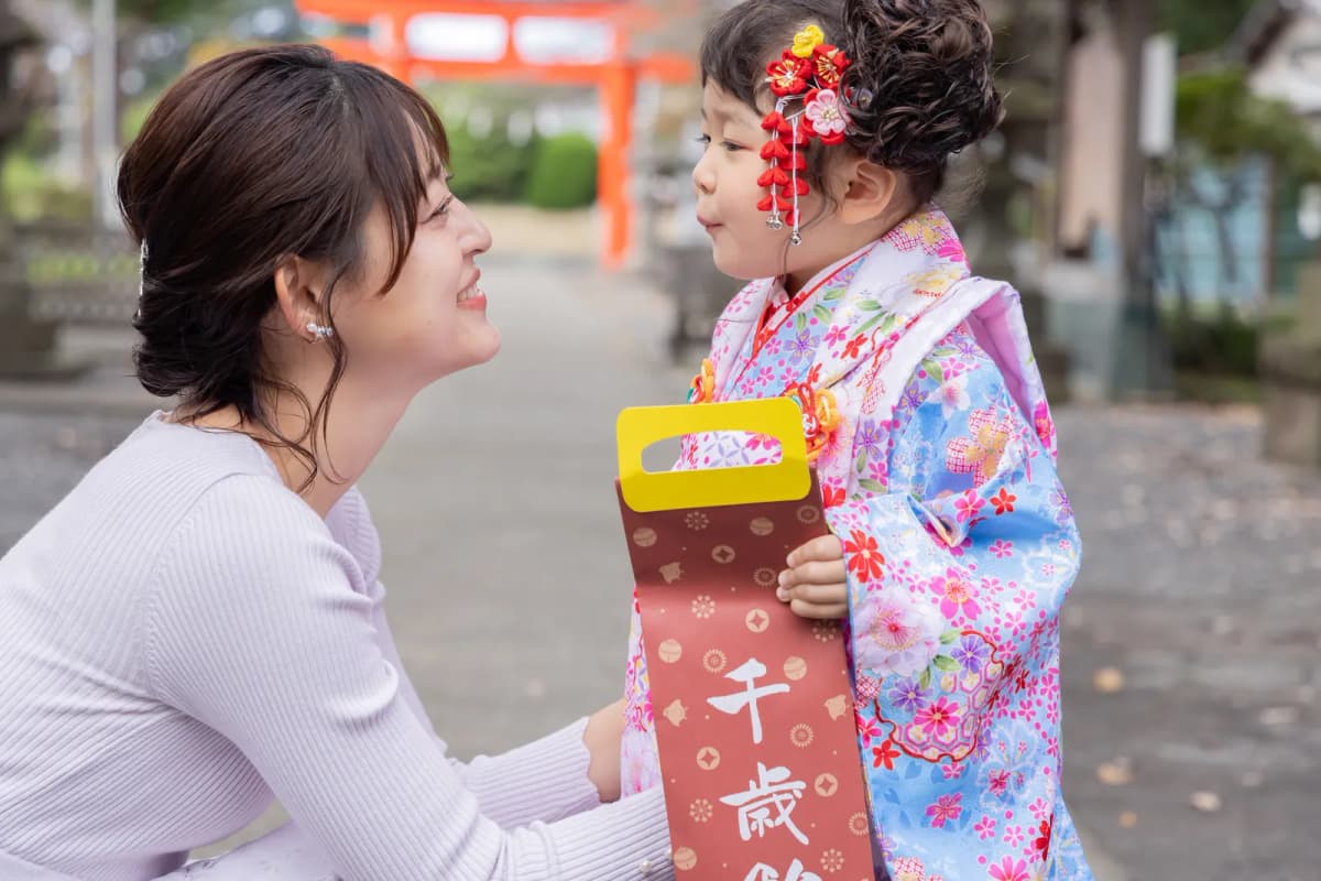 両親と手をつないで参道を歩く着物の女の子