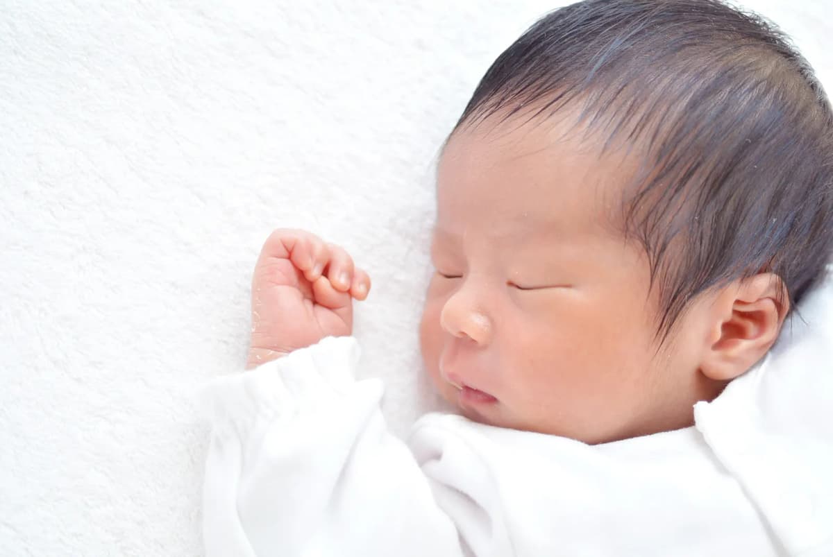白い布団で眠る新生児