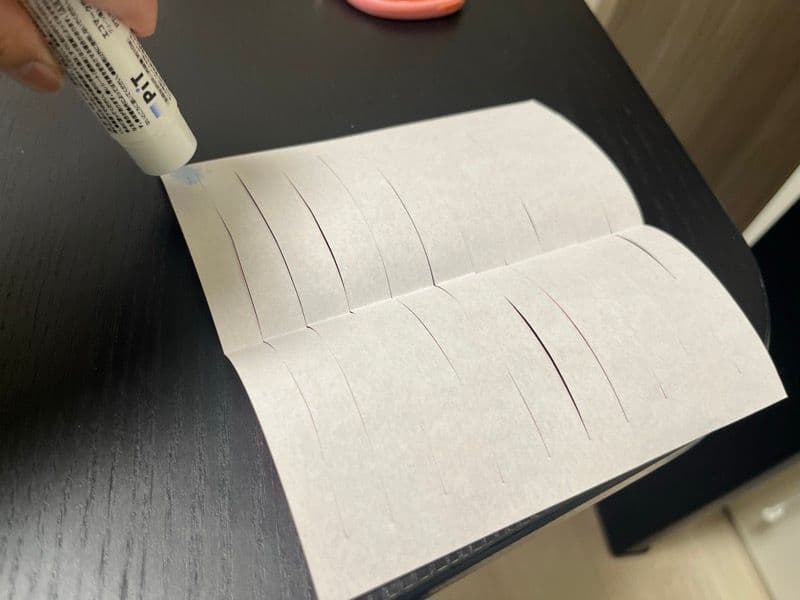 切り込みを入れた折り紙にのりを塗る