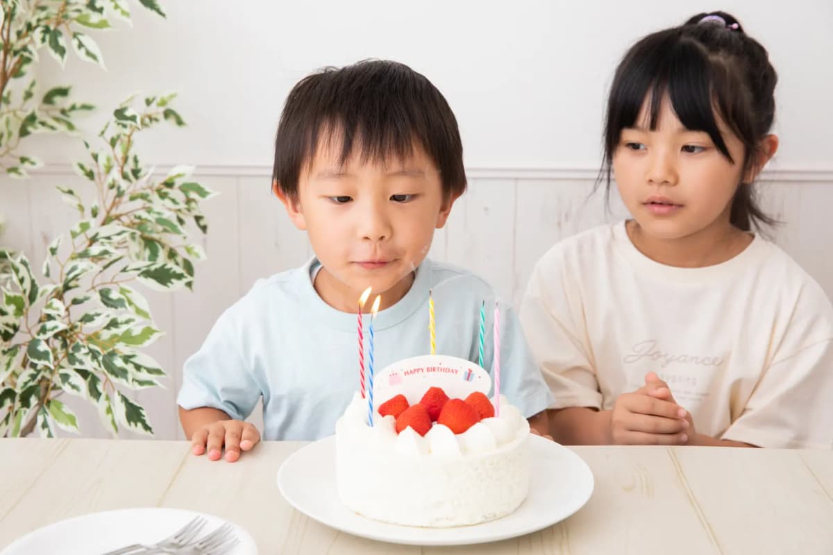 誕生日ケーキのろうそくを吹き消そうとする男の子