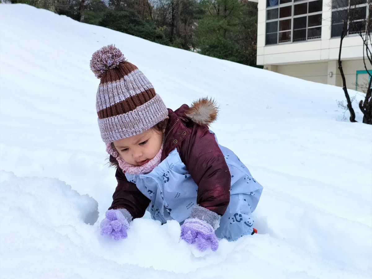 ニット帽をかぶって雪遊びをする子ども